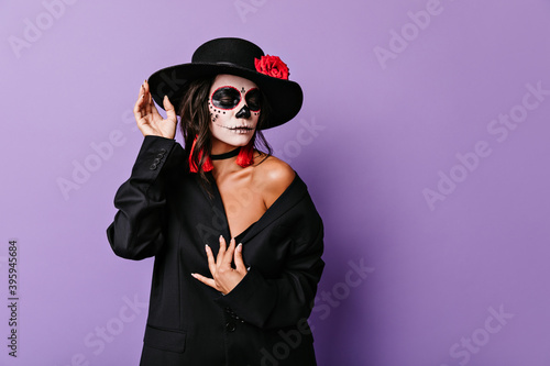 Coquettish woman lowered her eyes, posing in mafia clothes for portrait on Halloween