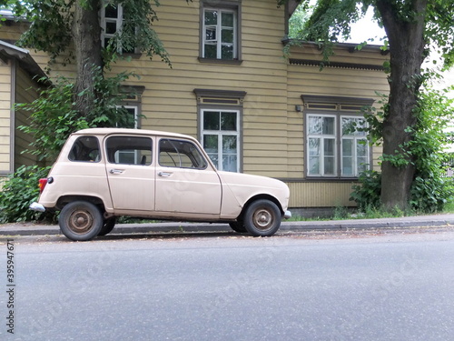Vintage car parking on the empty street. Old wooden house background.