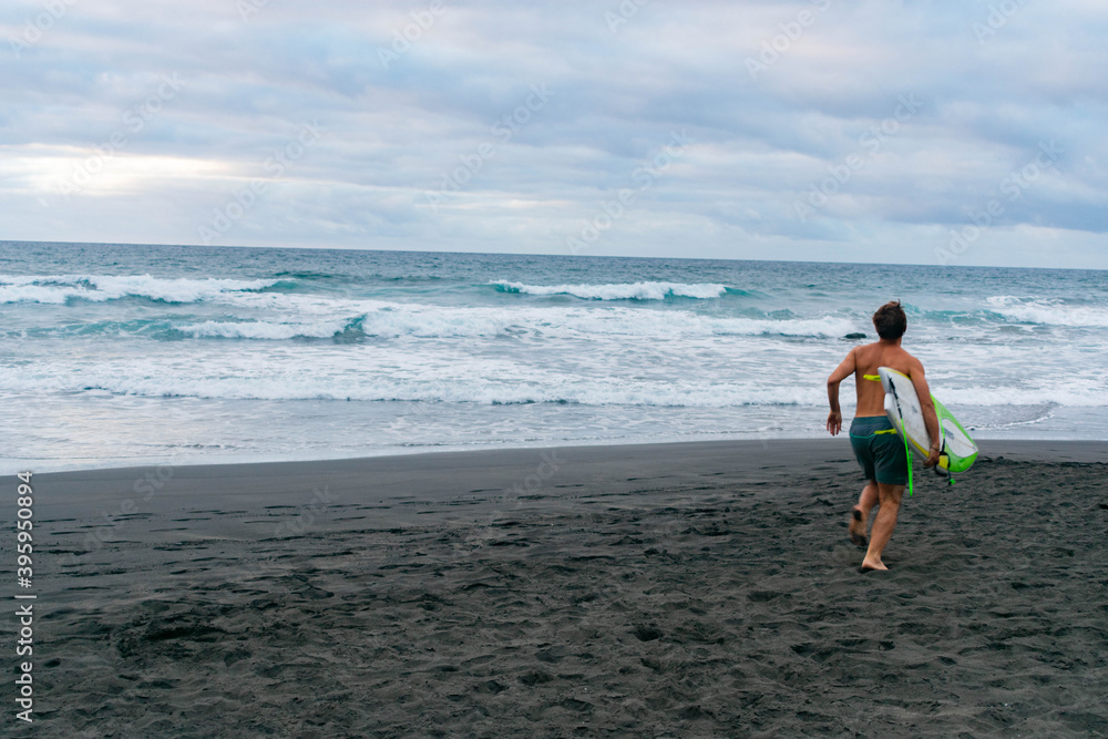 Person running on the beach going excited to surf Person running on the beach going excited to surf