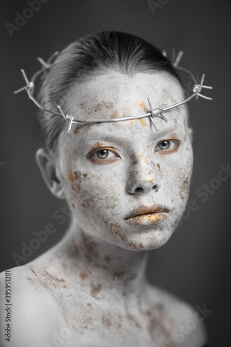 Portrait of young woman with marbled skin in a wreath of barbed wire.