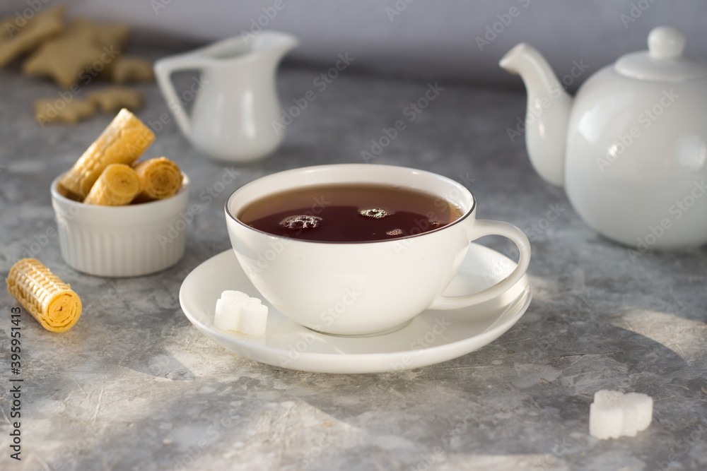 Tea from the teapot is poured into a white mug. A stream of tea pours into the Cup with a splash Tea from the teapot is poured into a white mug. A stream of tea pours into the Cup with a splash