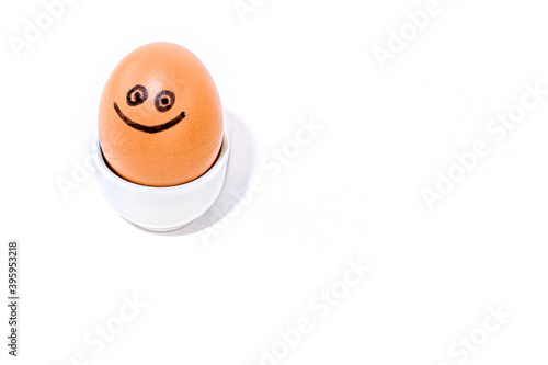 One single brown egg with positive face smiling in an egg stand on white background. Drawn black smile. photo