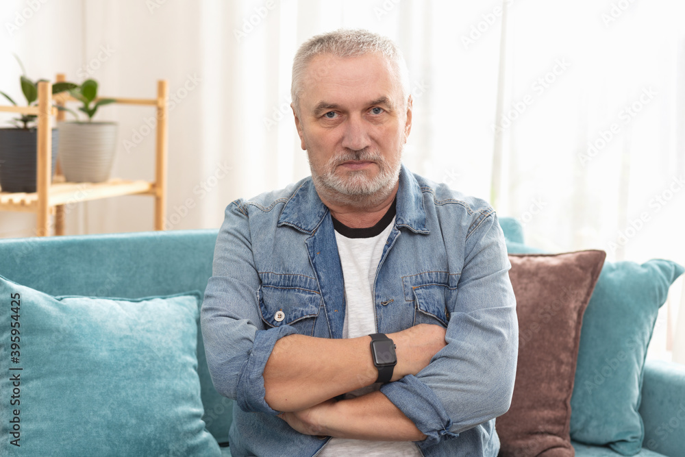 Portrait of gray-haired man, with serious angry face, with crossed arms on his chest