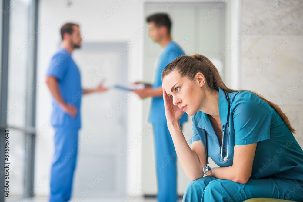 Obraz premium Young female doctor feeling upset while her colleagues talking