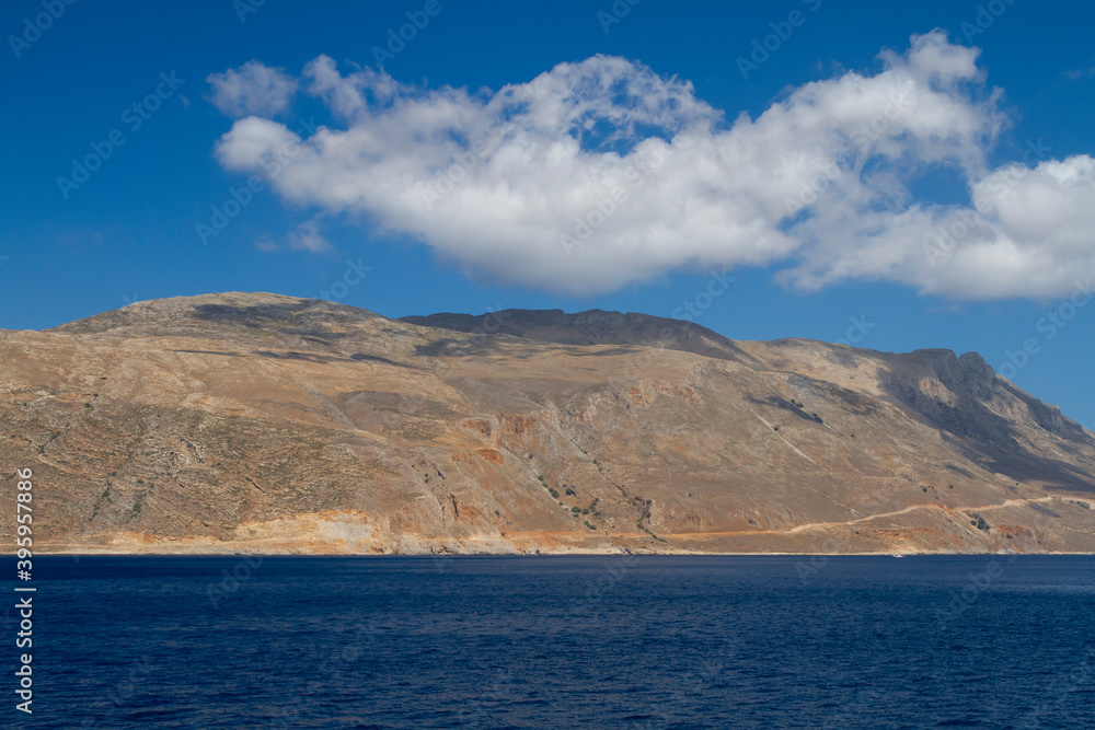 sea and the waves break on the rock and in the background is a mountain and clouds and a blue sky during the day sea and the waves break on the rock and in the background is a mountain and clouds and a blue sky during the day
