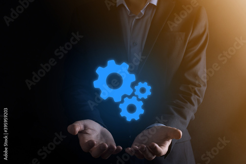 Business man in suit holding metal gears and cogwheels mechanism representing interaction teamwork concept,hand hold group of virtual cog gears wheel