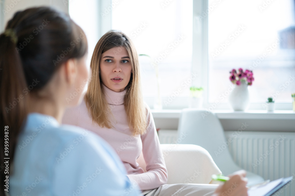 Patient talks about his problems to the psychotherapist sitting sofa in office. Patient talks about his problems to the psychotherapist sitting sofa in office.