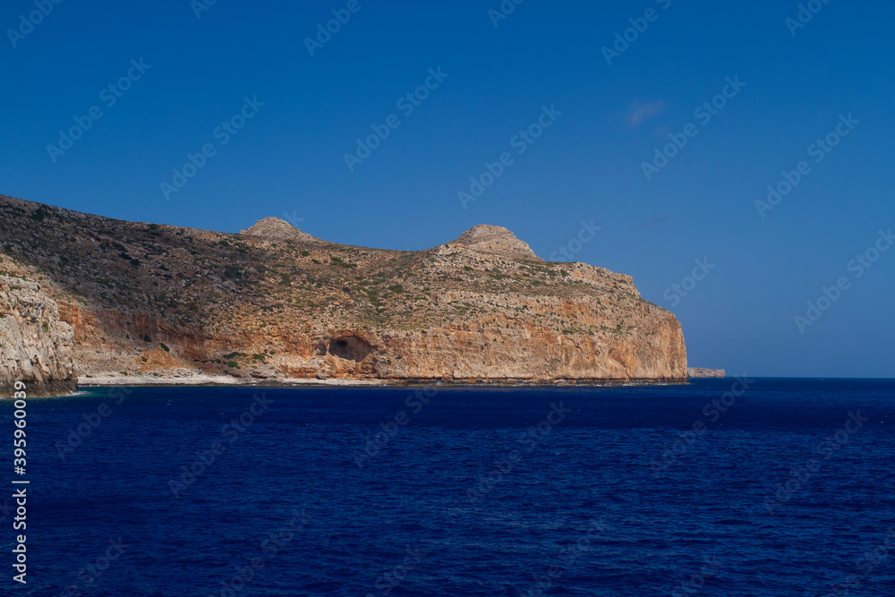 sea and the waves break on the rock and in the background is a mountain and clouds and a blue sky during the day sea and the waves break on the rock and in the background is a mountain and clouds and a blue sky during the day