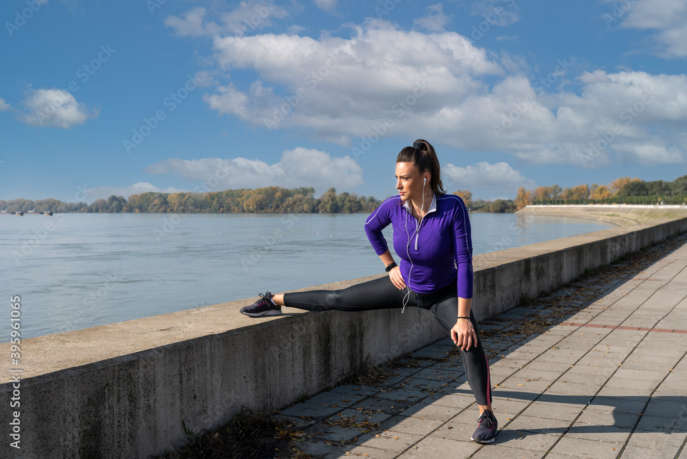 Young active athletic woman stretching her leg muscles as preparation for outdoor running exercise Young active athletic woman stretching her leg muscles as preparation for outdoor running exercise