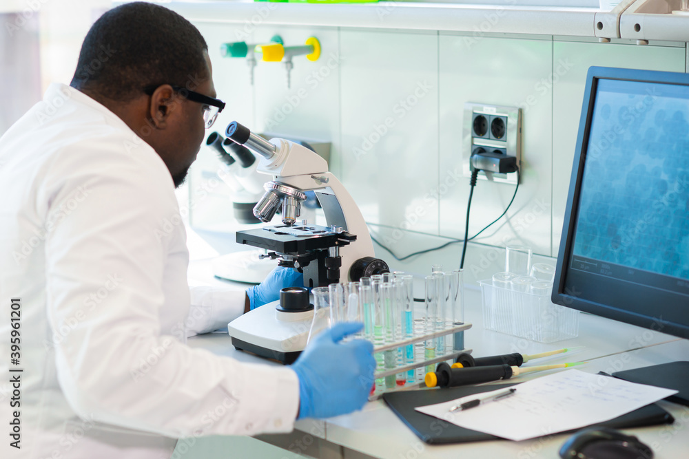African-american scientist working in lab. Doctor making microbiology research. Laboratory tools: microscope, test tubes, equipment. Biotechnology, chemistry, bacteriology, virology and health care. African-american scientist working in lab. Doctor making microbiology research. Laboratory tools: microscope, test tubes, equipment. Biotechnology, chemistry, bacteriology, virology and health care.