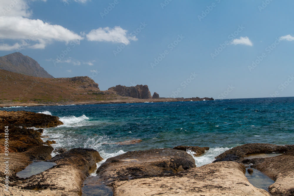 
sea ​​shore and waves on the surface and rocks on the shore during the day and clouds in the sky