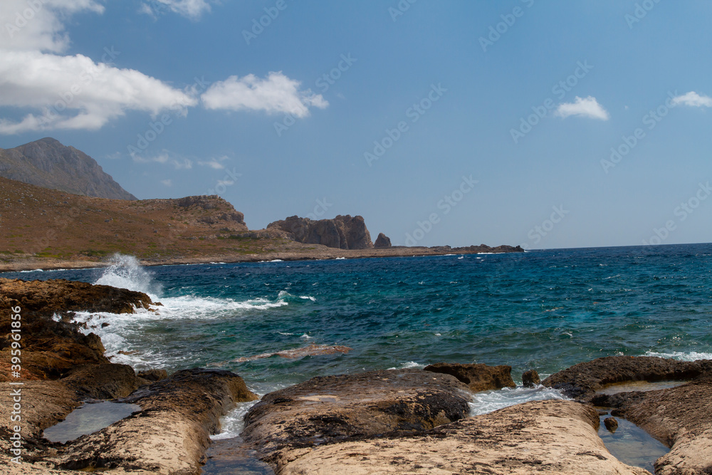 
sea ​​shore and waves on the surface and rocks on the shore during the day and clouds in the sky