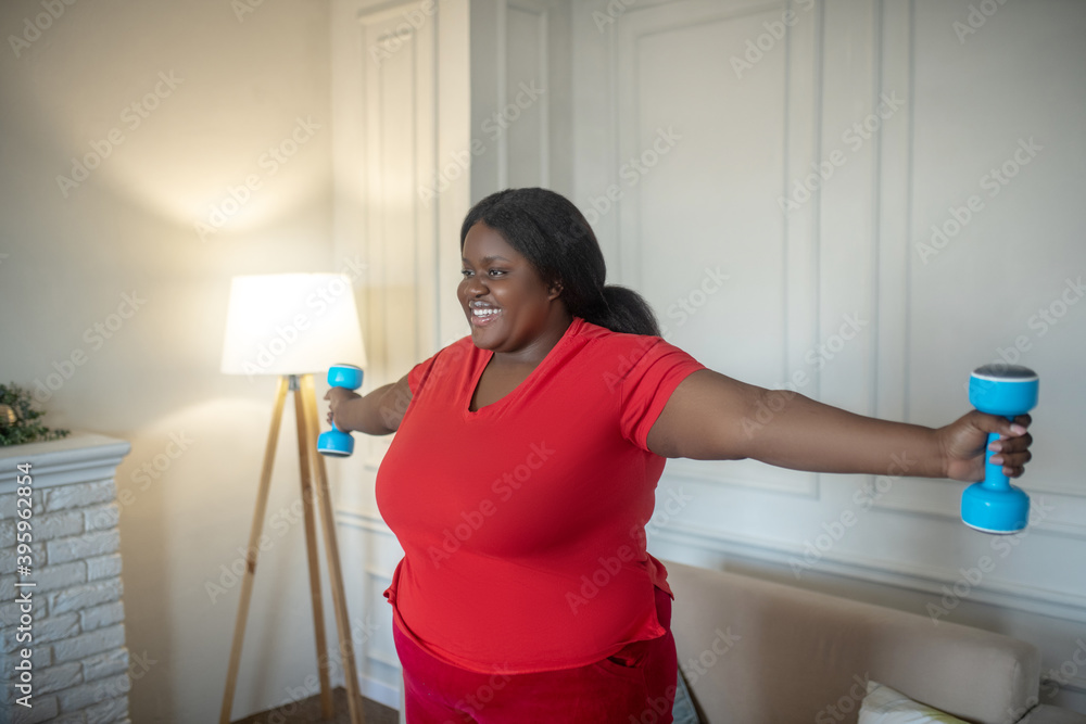Plus size african american woman having a workout with dumbbells Plus size african american woman having a workout with dumbbells