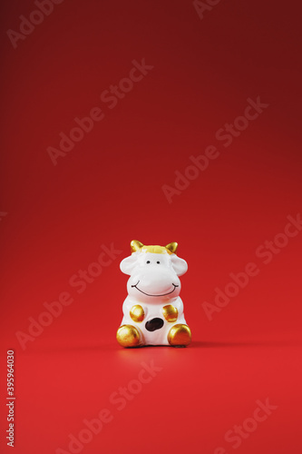 Cow figurine on a red background, new year's concept. Free space. © Alexander
