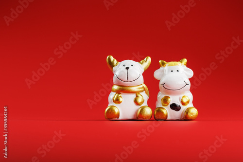 A pair of cow and bull Figures on a red background, with free space. © Alexander