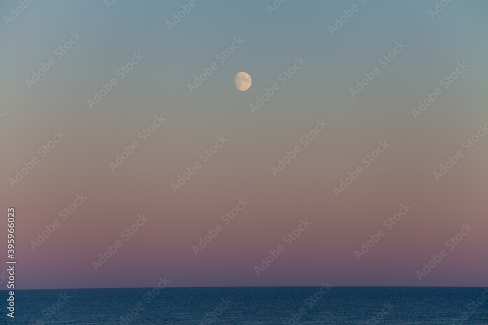 The moon over the ocean horizon in the Baltic Sea. Sunset during summertime.