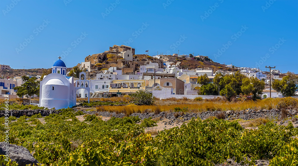 Blue domed church and vine fields in the settlement of Akortiri in Santorini in summertime