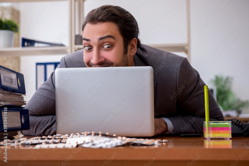Young male sick employee suffering at workplace Young male sick employee suffering at workplace