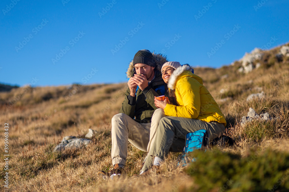 Happy couple drinking hot tea and enjoying the mountain view.