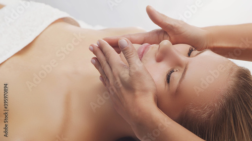 Young  beautiful and healthy woman in massaging salon. Traditional face massage therapy and skin care.