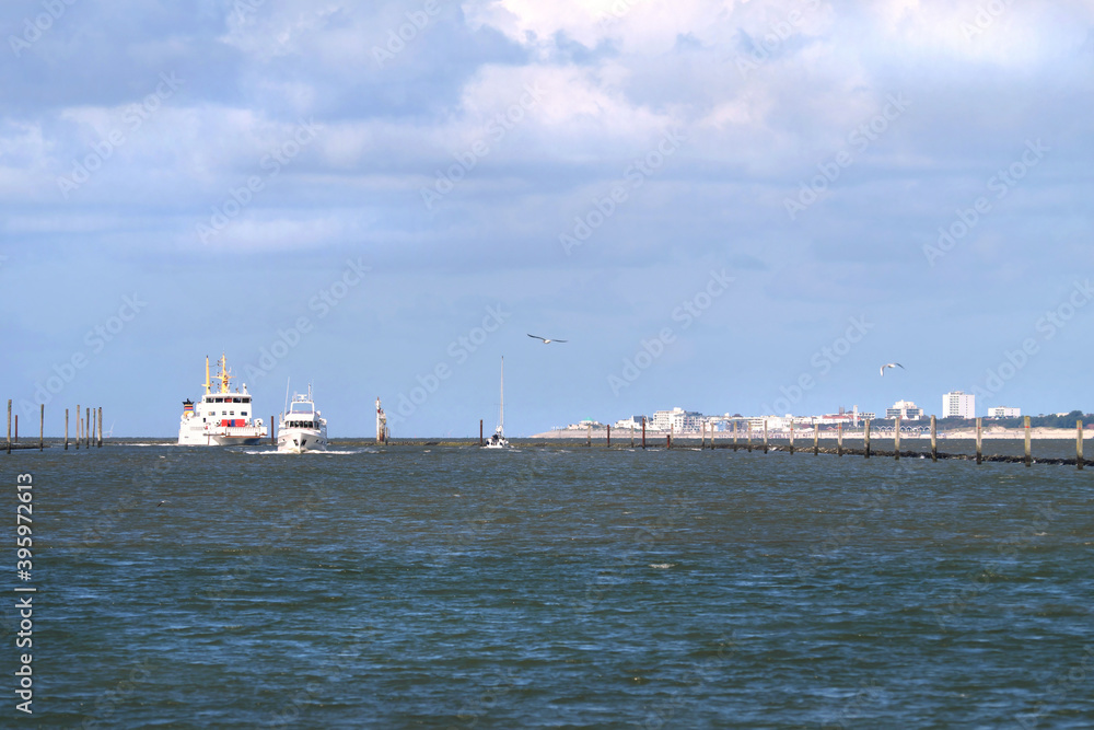 Panorama der Nordsee mit Norderney im Hintergrund und einfahrende Schiffe in den Hafen von Norddeich in Niedersachsen - Stockfoto
