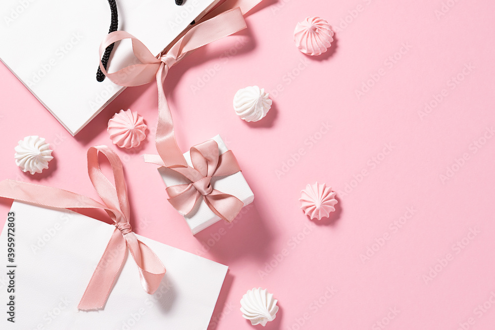 Holiday banner with gift paper bags, boxes and meringue cookies on pink pastel background. Birthday and St. Valentine’s Day greeting card concept.
