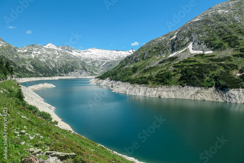Fototapeta Naklejka Na Ścianę i Meble -  Dam in Austrian Alps. The artificial lake stretches over a vast territory, shining with navy blue color. The dam is surrounded by high mountains. In the back there is a glacier. Controlling the nature