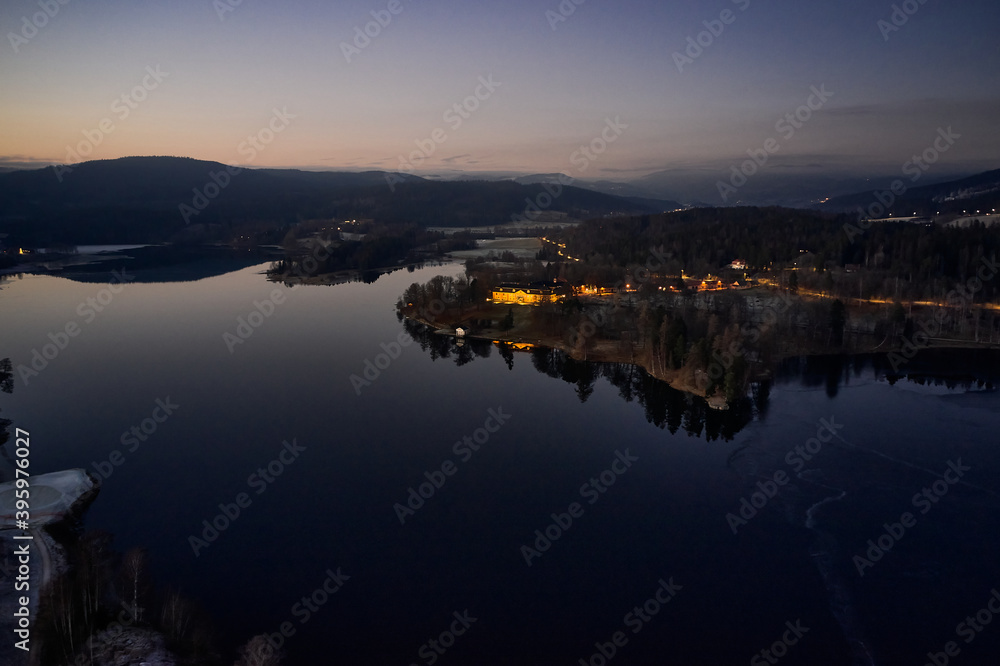 Drone or aerial photo from Oslo, Norway. Shot in late November in blue hours.  Winter is coming. Ground and trees are covered with snow frost, the lakes are freezing up.