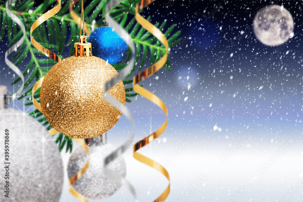 Christmas decoration. Golden and silver balls, streamers hanging on spruce branch on blue snowy background. Christmas card with copy space. Xmas and New Year background.