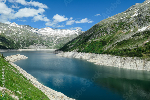 Dam in Austrian Alps. The artificial lake stretches over a vast territory, shining with navy blue color. The dam is surrounded by high mountains. In the back there is a glacier. Controlling the nature © Chris