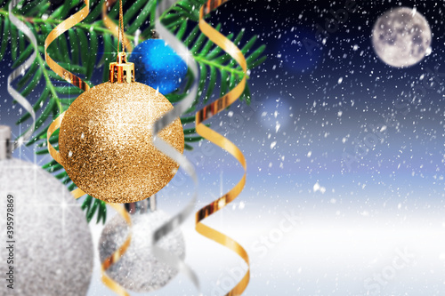 Obraz na płótnie Christmas decoration. Golden and silver balls, streamers hanging on spruce branch on blue snowy background. Christmas card with copy space. Xmas and New Year background. w salonie