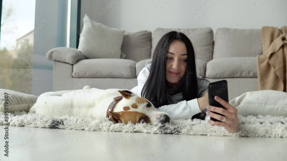 Young woman takes a selfie with her dog and use phone in a beautiful modern apartment Young woman takes a selfie with her dog and use phone in a beautiful modern apartment