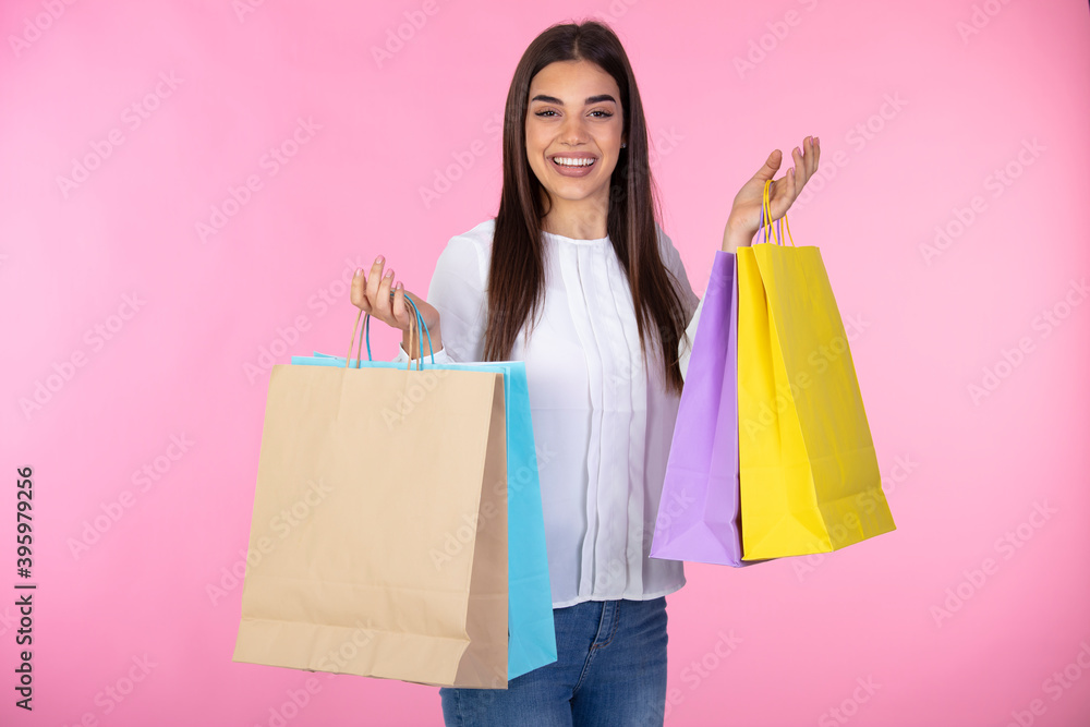 Studio portrait of a beautiful young woman, in a white outfit, holding in her hands a few shopping bags. she is laughing and looking very happy. Shopping woman holding shopping bags 