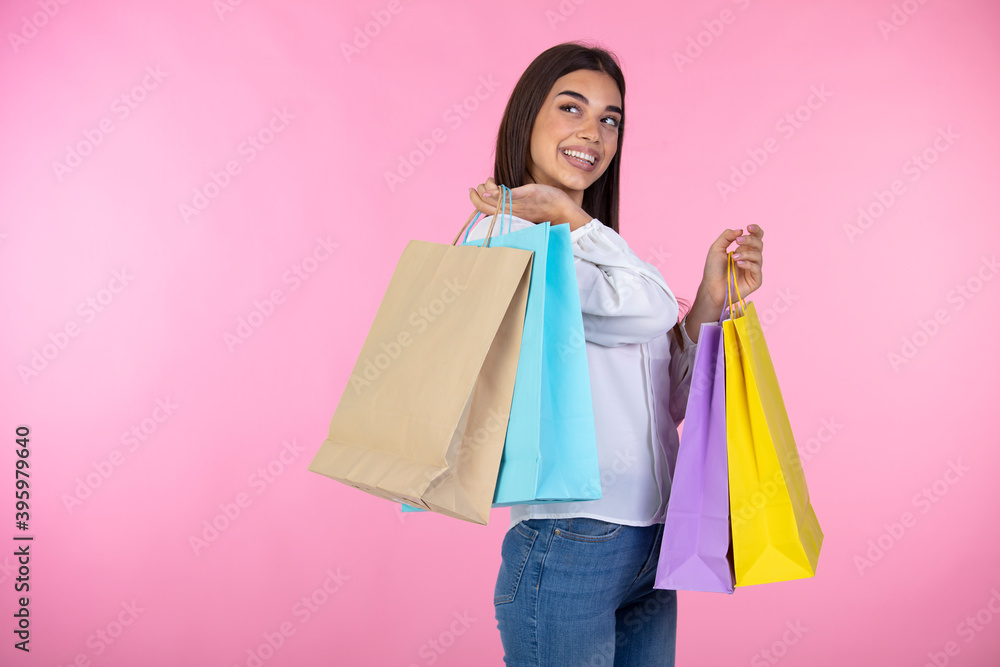 Pleasant woman enjoying shopping. Amazing brunette girl posing with shopping bags. Shopping woman happy smiling holding shopping bags isolated on pink background Pleasant woman enjoying shopping. Amazing brunette girl posing with shopping bags. Shopping woman happy smiling holding shopping bags isolated on pink background