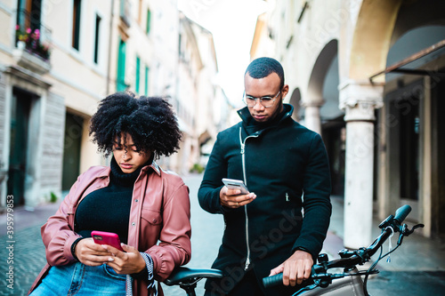 Couple with cellphone sitting on bicycle.