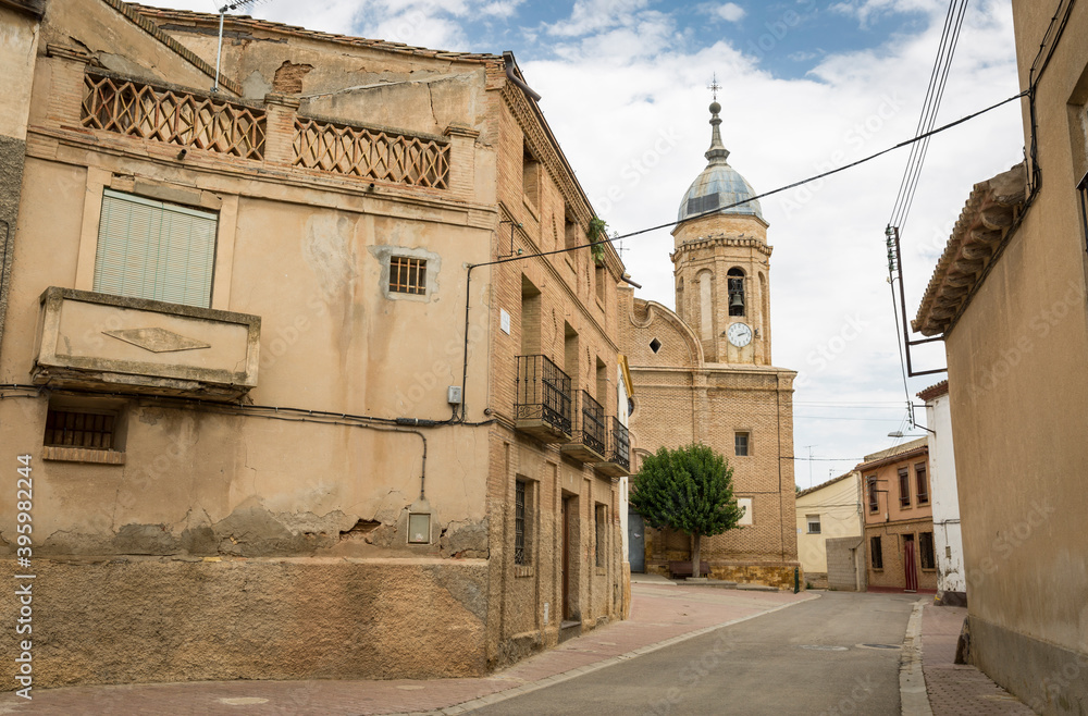 a street with typical houses and the Parish Church of the Holy Trinity in Alcala de Ebro, province of Zaragoza, Aragon, Spain