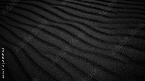 Black Sand dune. Black Sand beach macro photography. Background, texture, wave pattern of oceanic sand on the beach, black. Texture of beach sand. Black beach.