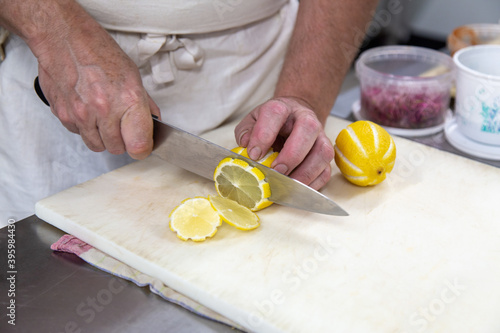 Chef cuisinier qui coupe des citrons sur une planche à découper avec un couteau