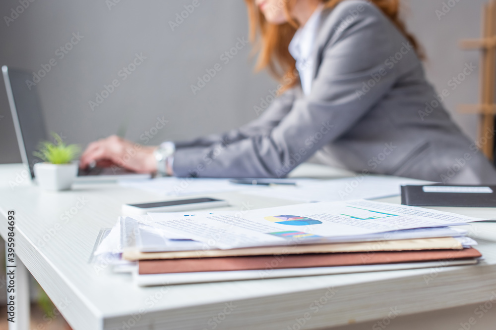 Cropped view of lawyer typing on laptop, while sitting at workplace with pile of documents on blurred Cropped view of lawyer typing on laptop, while sitting at workplace with pile of documents on blurred