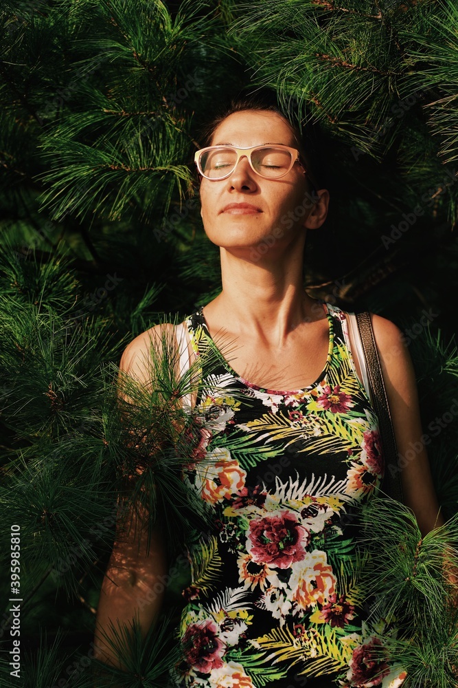 portrait of a young woman among pine tree branches portrait of a young woman among pine tree branches