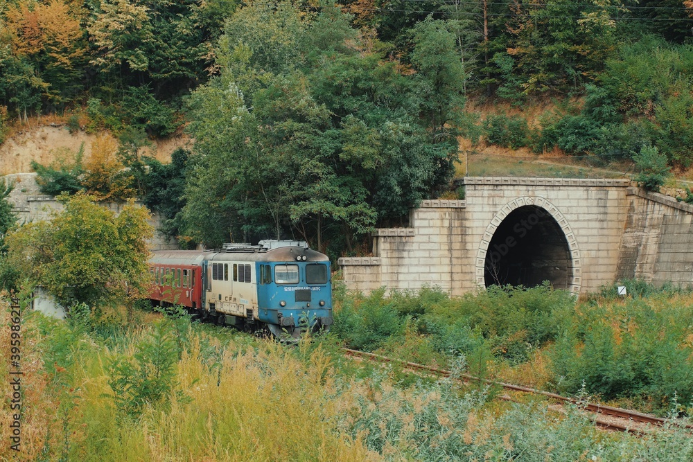 Fototapeta premium Train speeding at the exit of a tunnel in an remote mountain area