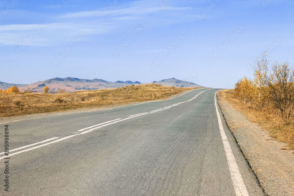 Naklejka premium asphalt road in the desert with mountains in the background stretching beyond the horizon