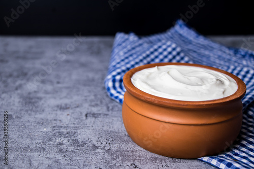 Greek strained yogurt in traditional bowl on a grey background