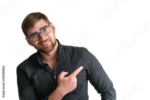 Portrait of a happy handsome bearded glasses businessman in eyeglasses and black shirt pointing finger away over isolated white background
