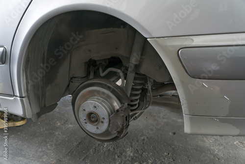 Passenger car on lifter in garage for inspect or service rear suspension and disc brake, caliper, lining, bush, tie rod, bearing and shock absorber. Image for advertise in service business, spare part