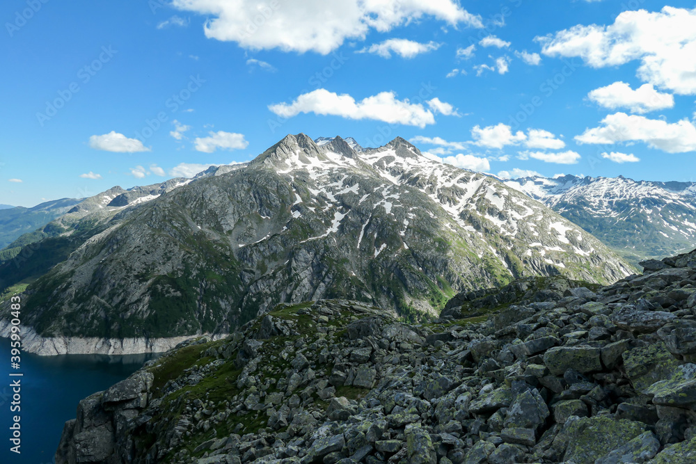 Obraz premium Dam in Austrian Alps. The artificial lake stretches over a vast territory, shining with navy blue color. The dam is surrounded by high mountains. In the back there is a glacier. Controlling the nature