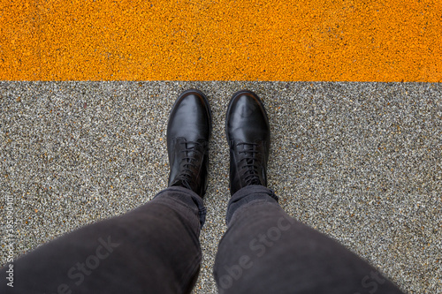 Black shoes standing on the asphalt concrete floor with orange line. Feet shoes walking in outdoor. Youth Selphie Modern hipster photo