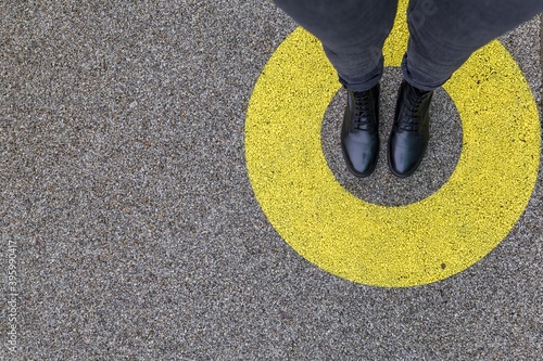 Black shoes standing in yellow circle on the asphalt concrete floor. Comfort zone or frame concept. Feet standing inside comfort zone circle. Place for text, banner photo