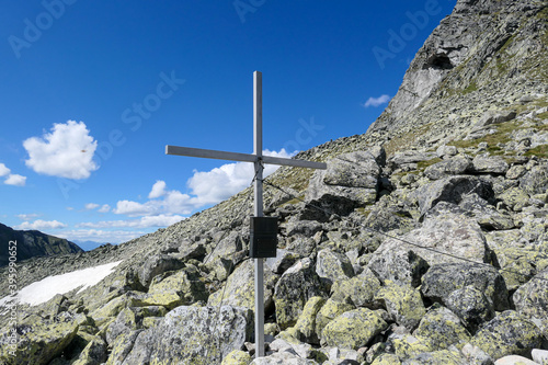 A wooden cross on top of Arlhöhe in Maltal region in Austrian Alps. The cross is surrounded by lose stones and boulders. Summer in the mountains. Serenity and achievement. photo