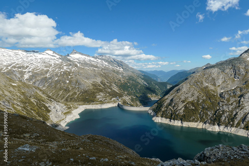 Dam in Austrian Alps. The artificial lake stretches over a vast territory, shining with navy blue color. The dam is surrounded by high mountains. In the back there is a glacier. Controlling the nature © Chris